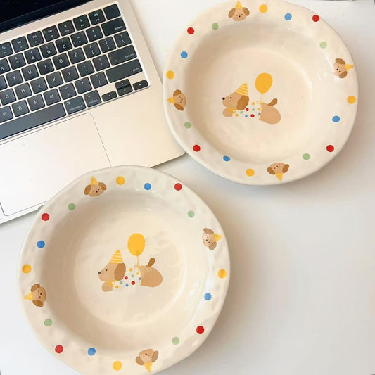 Child's plate with cartoon dog design held by a hand, laptop in the background