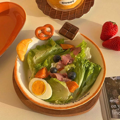Hand-painted ceramic deep plate with salad showing 3D bread decorations: croissant, pretzel, chocolate, 21CM