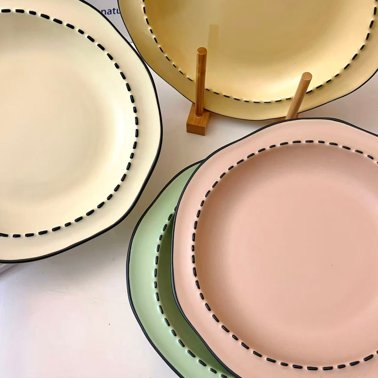 Four macaron color ceramic plates: off-white, yellow, matcha green, pink with manga style black rim