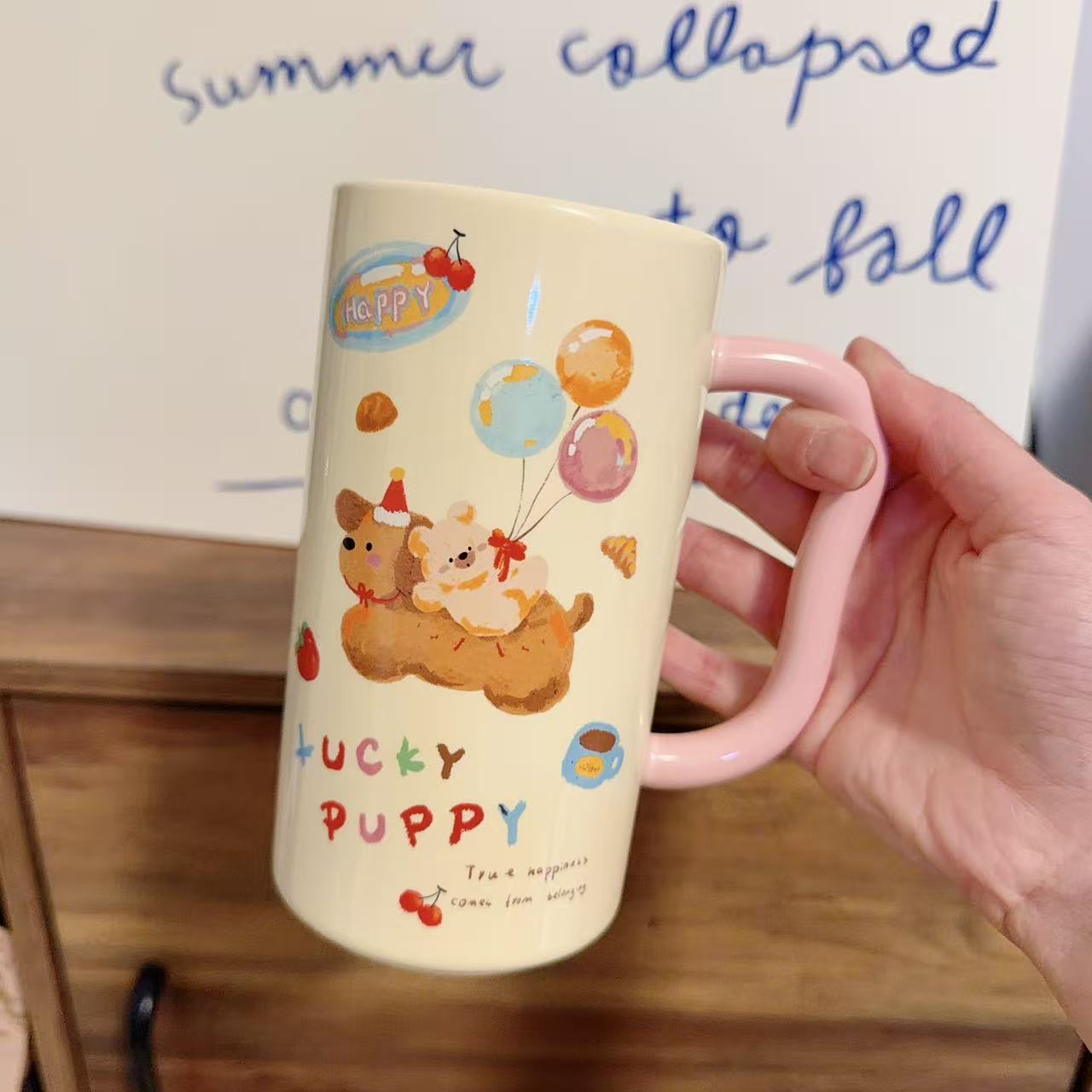 Mug with cartoon dogs and 'Lucky Puppy' text held by a hand on a wooden surface.