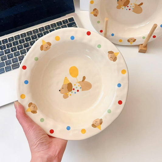 Child's plate with cartoon dog design held by a hand, laptop in the background