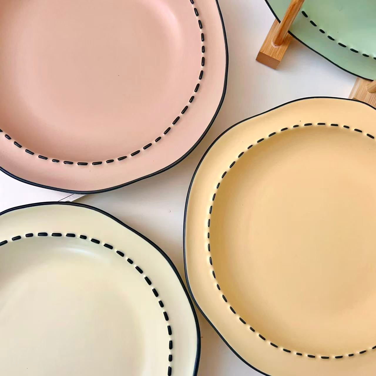 Four macaron color ceramic plates: off-white, yellow, matcha green, pink with manga style black rim