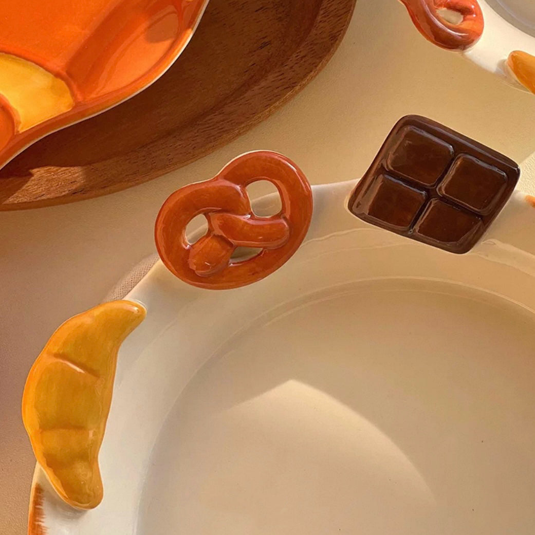Hand-painted ceramic deep plate with salad showing 3D bread decorations: croissant, pretzel, chocolate, 21CM
